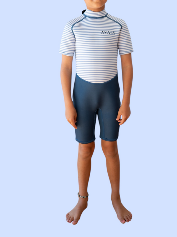 Child wearing Navy Stripe Kids Wetsuit with blue and white striped top and navy shorts in front view