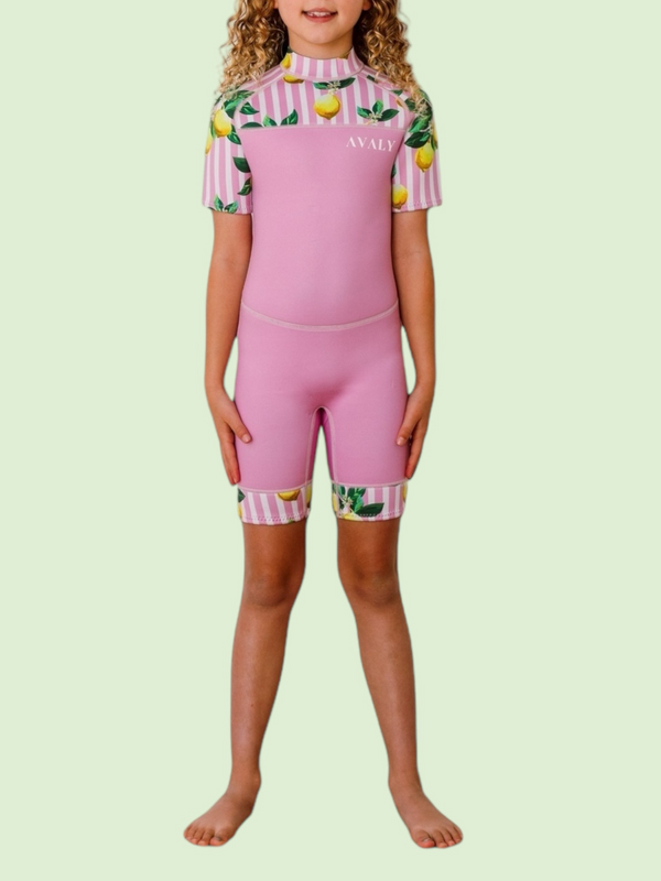 Girl wearing Pink Lemon Stripe Kids Wetsuit with pink base and lemon print striped sleeves and leg cuffs