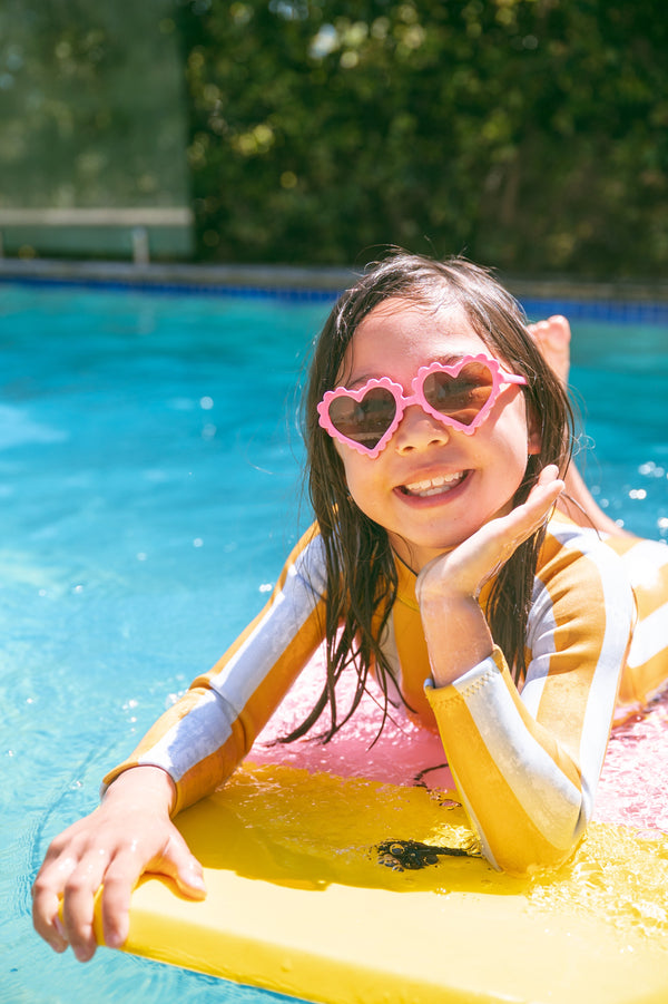 Girl swimming happily in pool wearing AVALY rashie - eczema-friendly swimwear