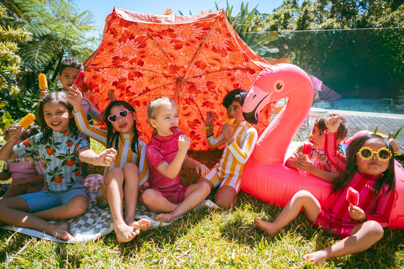 Group of kids in AVALY swimwear enjoying sun under umbrella