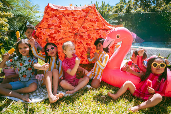 Group of kids in AVALY swimwear enjoying sun under umbrella