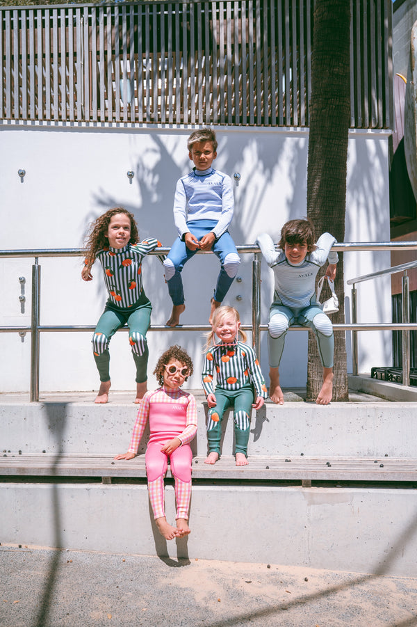 Group of kids in AVALY wetsuits at the beach — why kids should keep swimming through winter