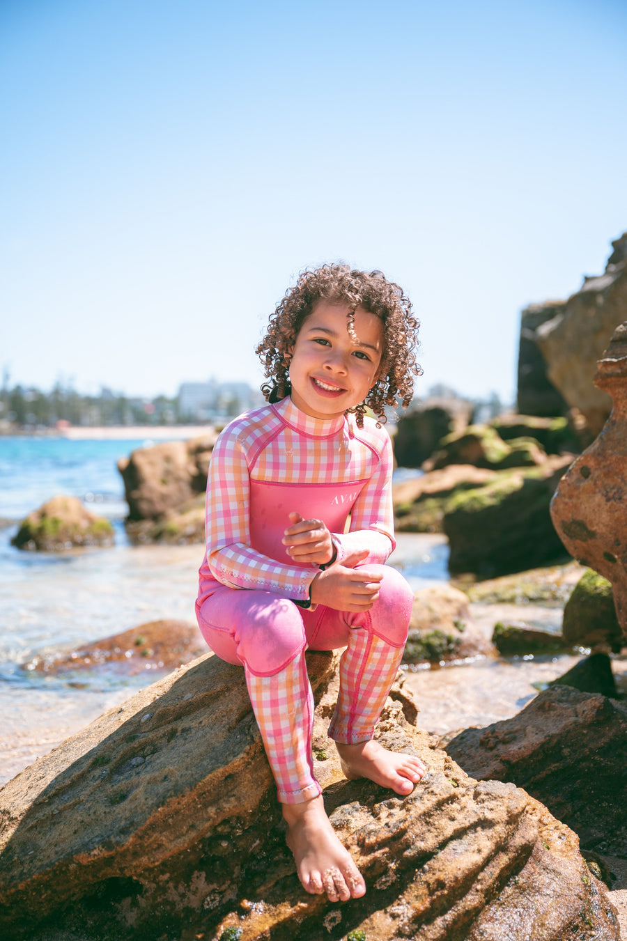 Child exploring rock pools in AVALY swimwear on the Australian coast