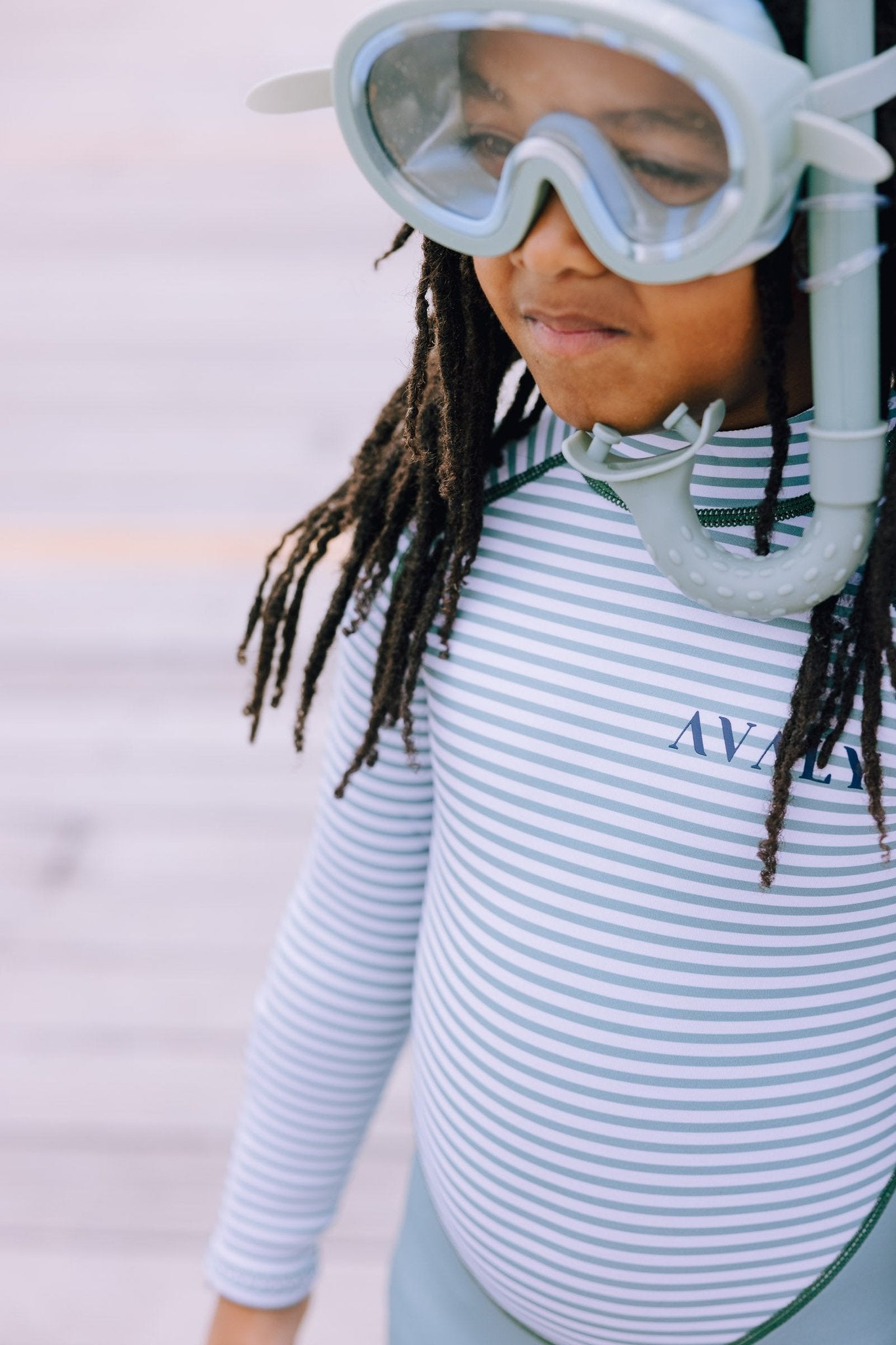 Child model wearing Green Striped Kids Sustainable Wetsuit with snorkel mask, showing white and green horizontal stripes