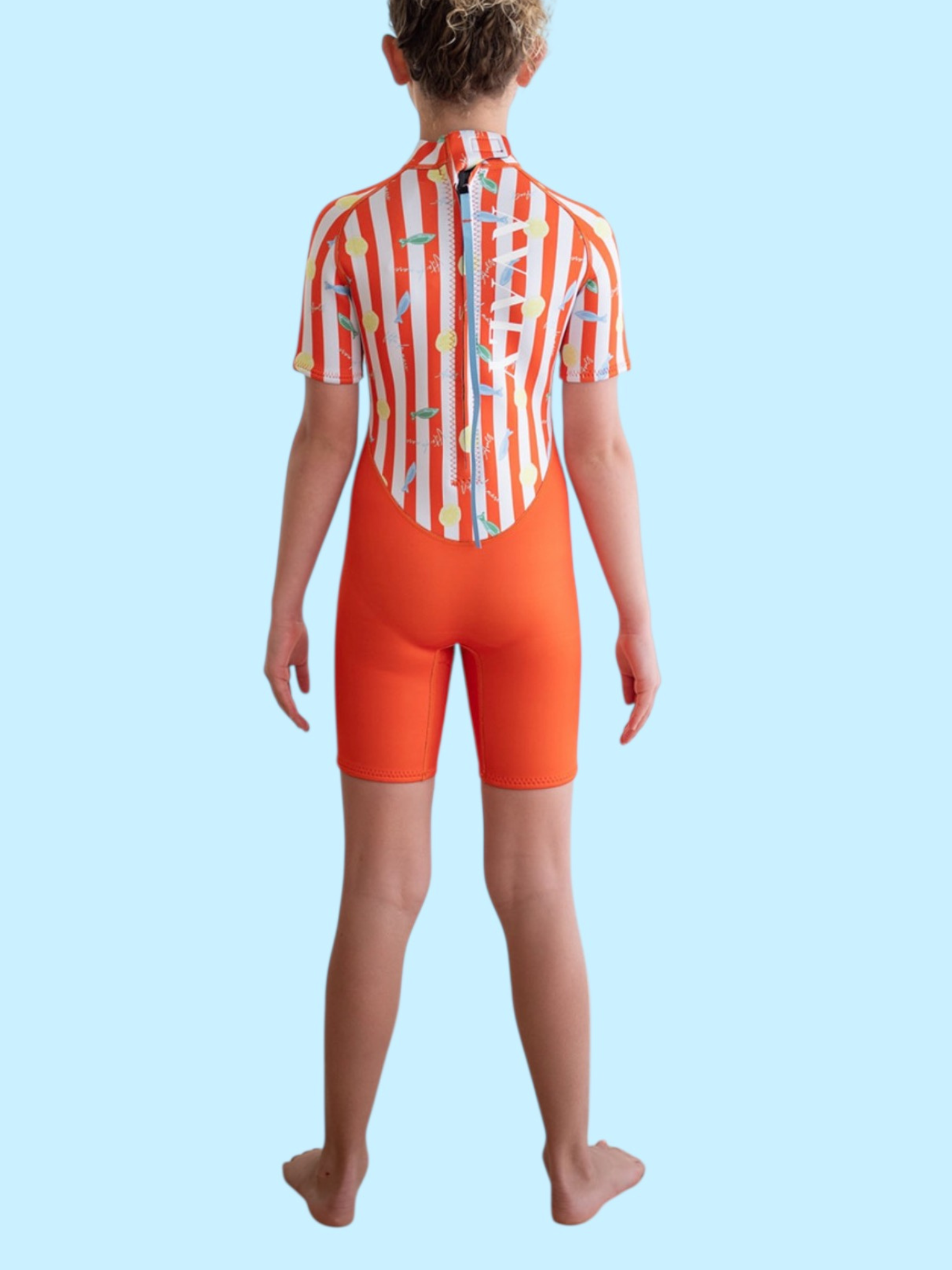 Back view of child wearing Amalfi Fish Kids Wetsuit showing orange and white striped pattern with colorful fish print