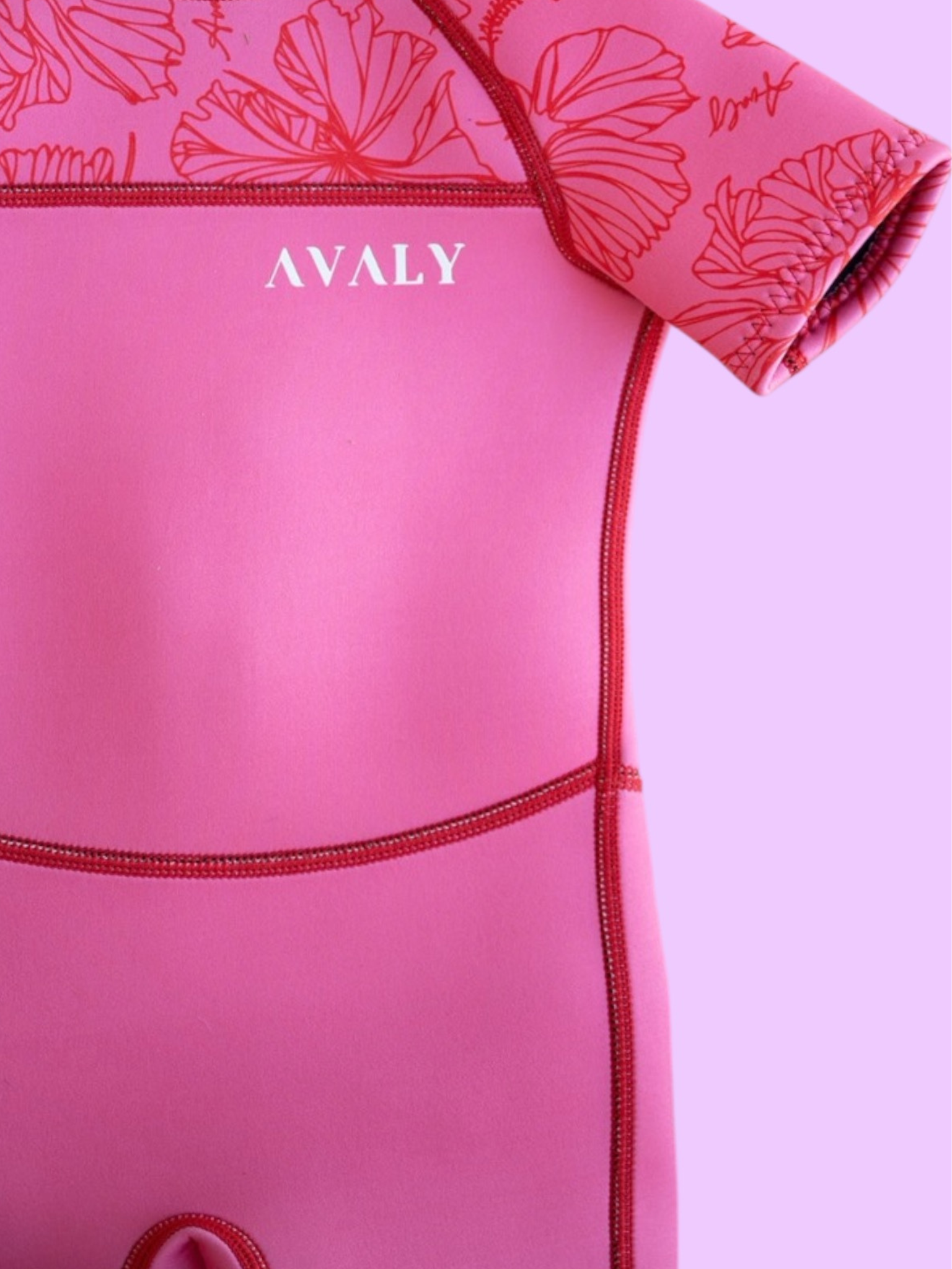 Close up detail of Pink Hibiscus Kids Wetsuit showing red contrast stitching and floral print pattern on sleeves
