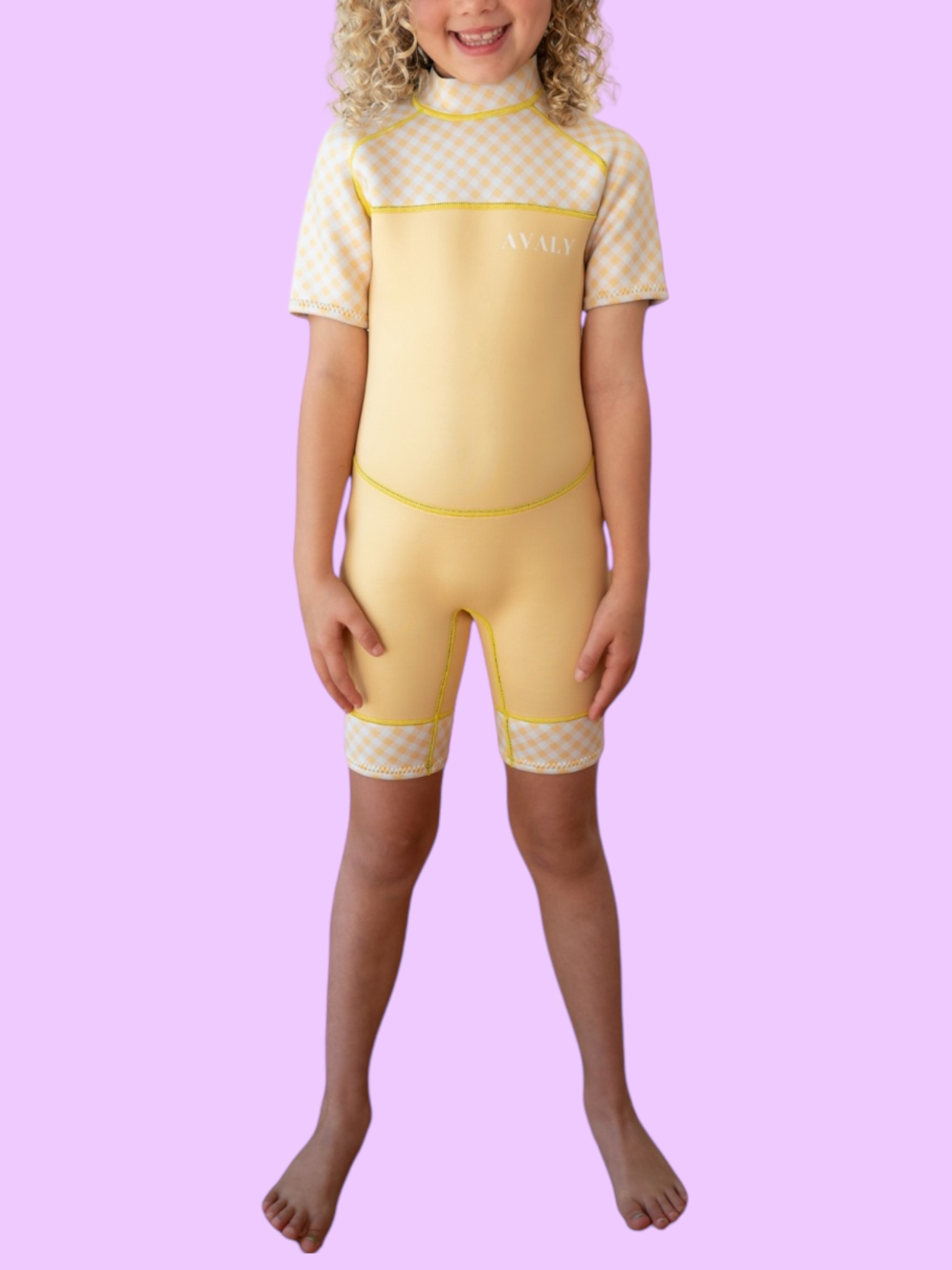 Child model wearing Yellow Gingham Kids Wetsuit with checkered pattern panel on chest and legs