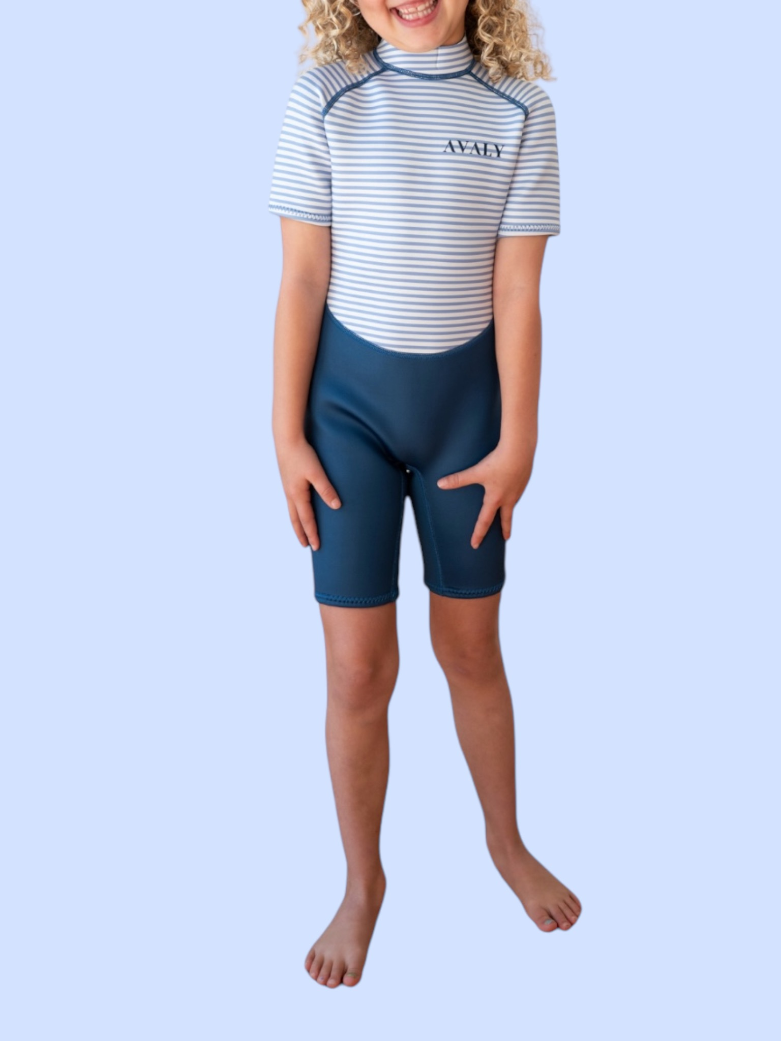 Child model wearing Navy Stripe Kids Wetsuit with blue and white striped top and navy shorts against light background