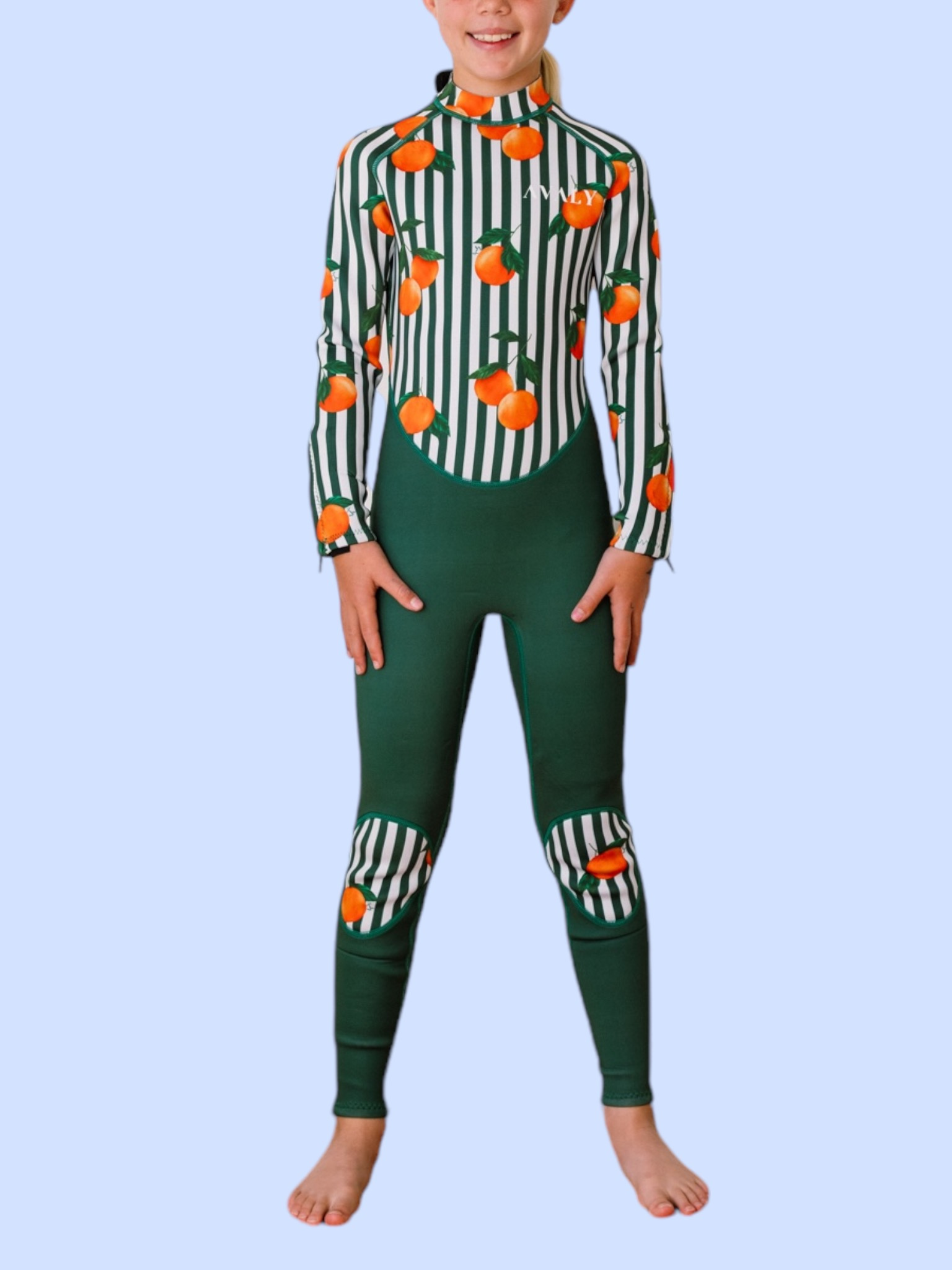 Child model wearing Forest Green & Mandarins wetsuit with orange citrus print on green and white striped pattern
