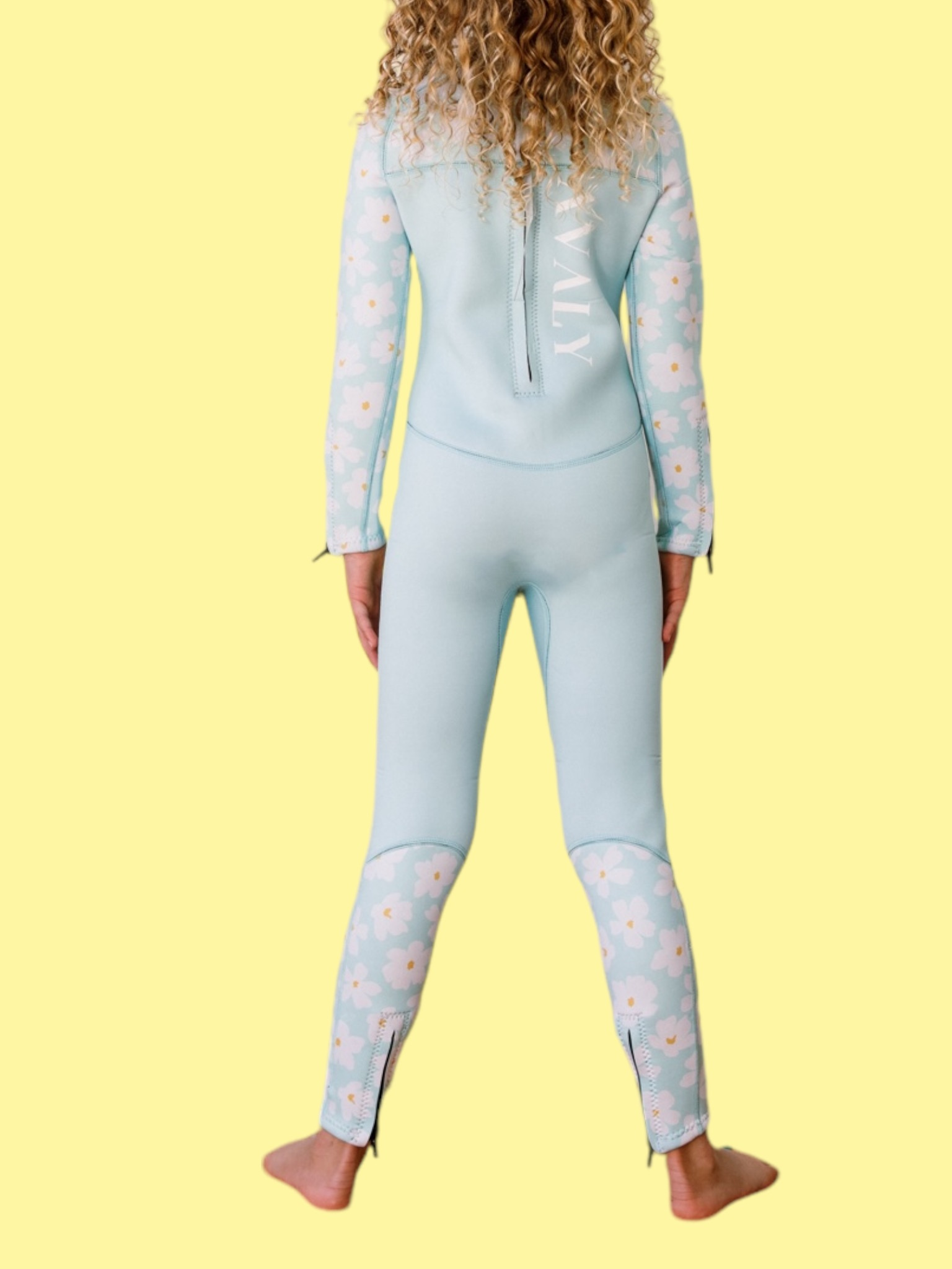 Back view of child wearing Mint Daisy wetsuit showing light blue body with white daisy print sleeves and leg panels
