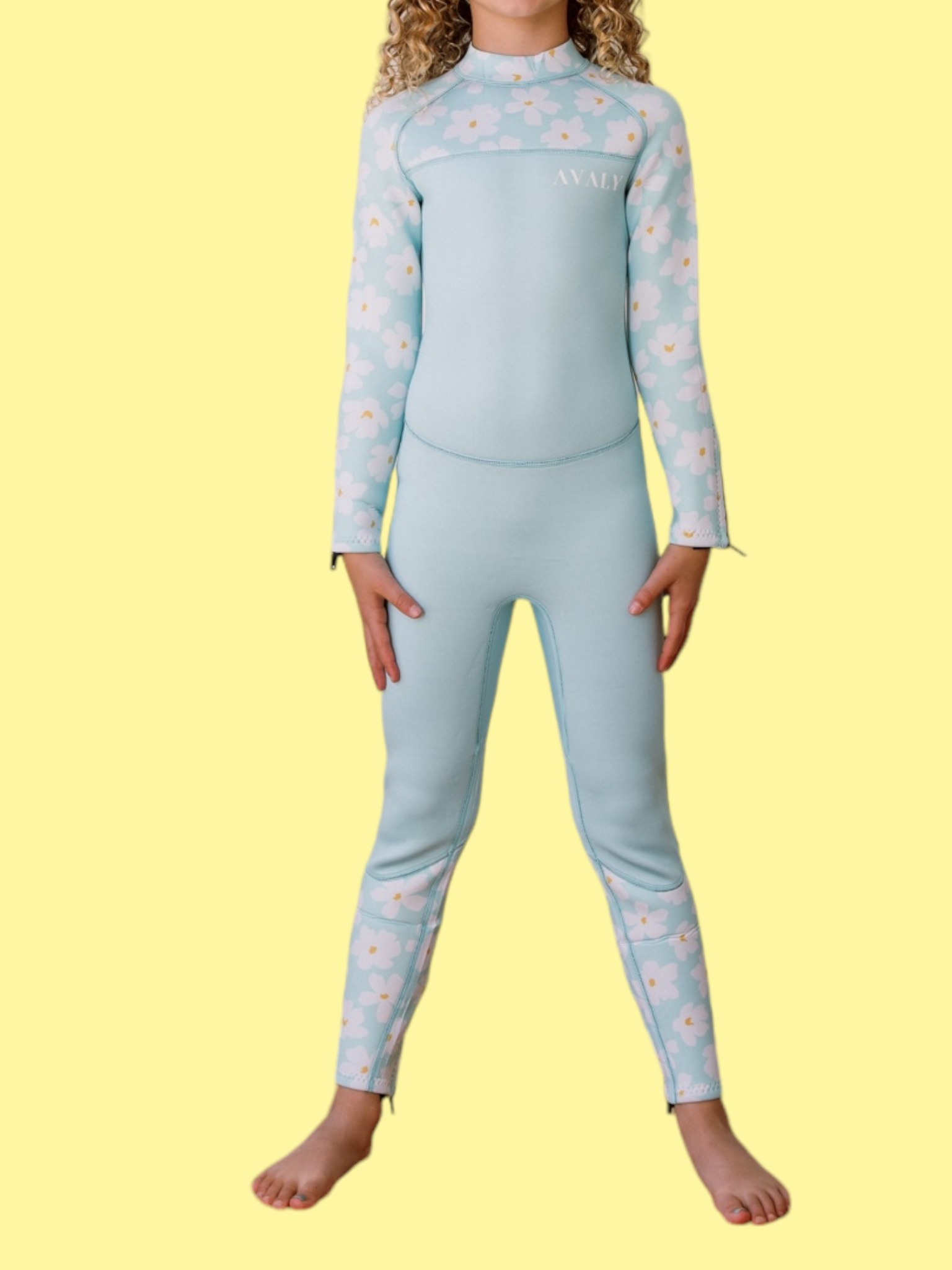 Child model wearing Mint Daisy wetsuit in light blue with white daisy pattern on sleeves and lower legs
