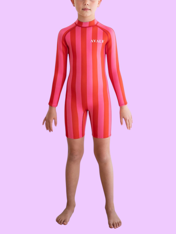 Child model wearing Pink & Red Stripe Kids Wetsuit with vertical striped pattern and long sleeves