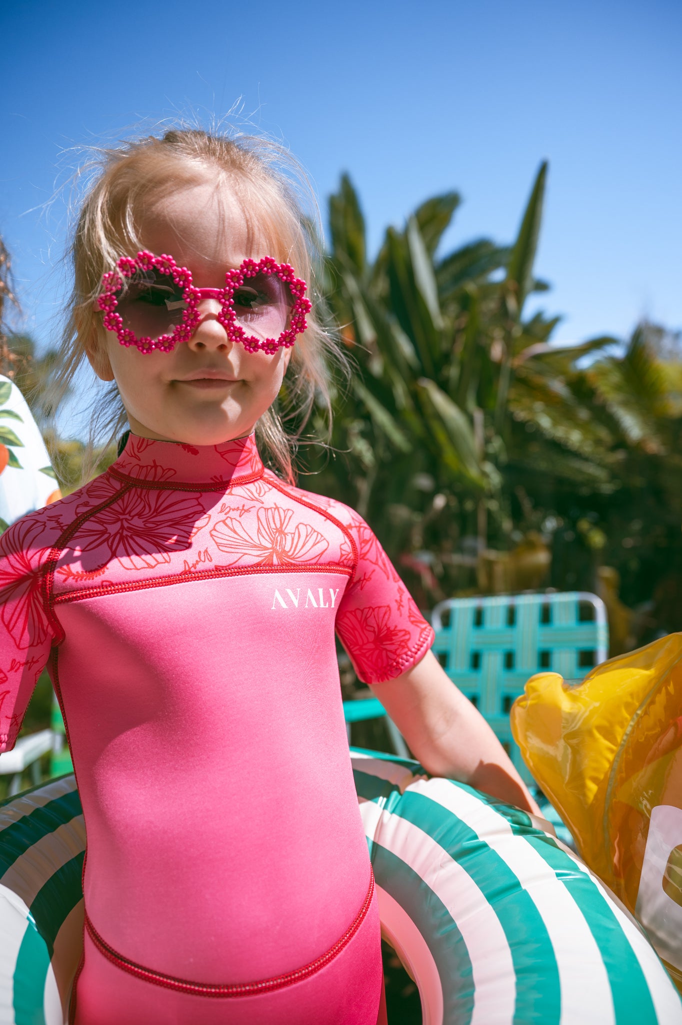 Girl in pink floral springsuit with flower sunglasses