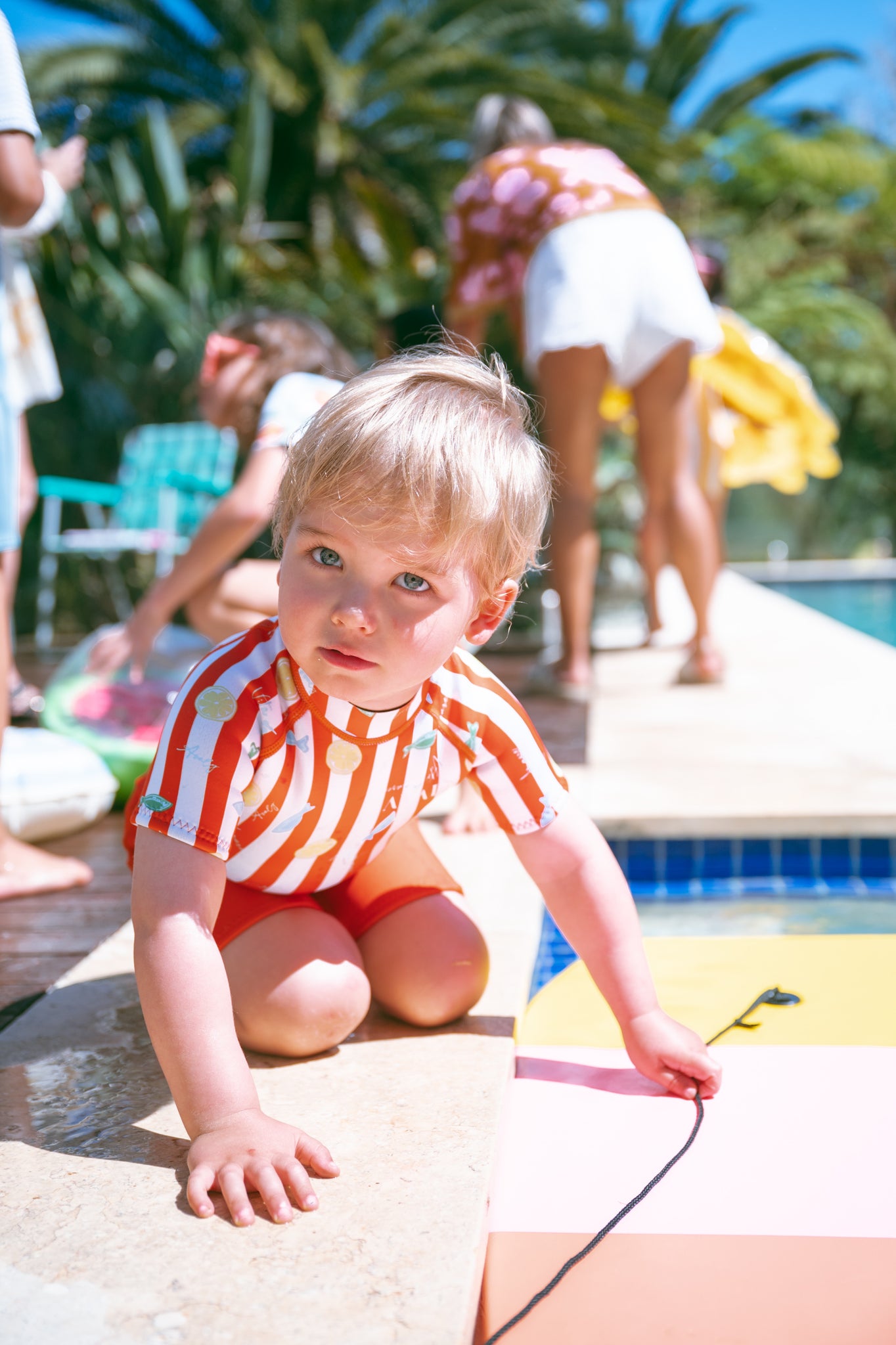 Toddler in red striped AVALY springsuit by the pool
