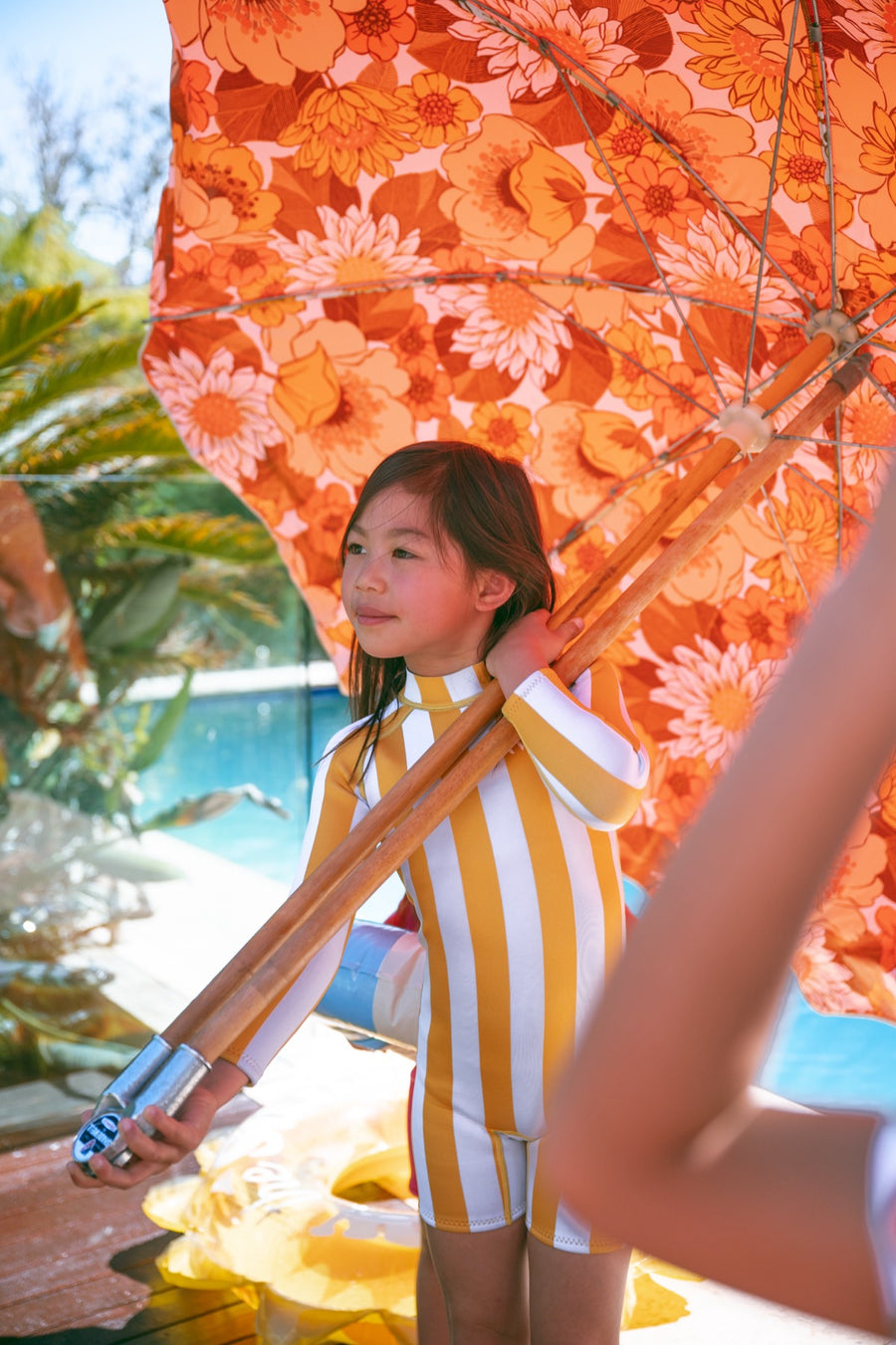 Girl in an AVALY yellow stripe springsuit under a retro beach umbrella
