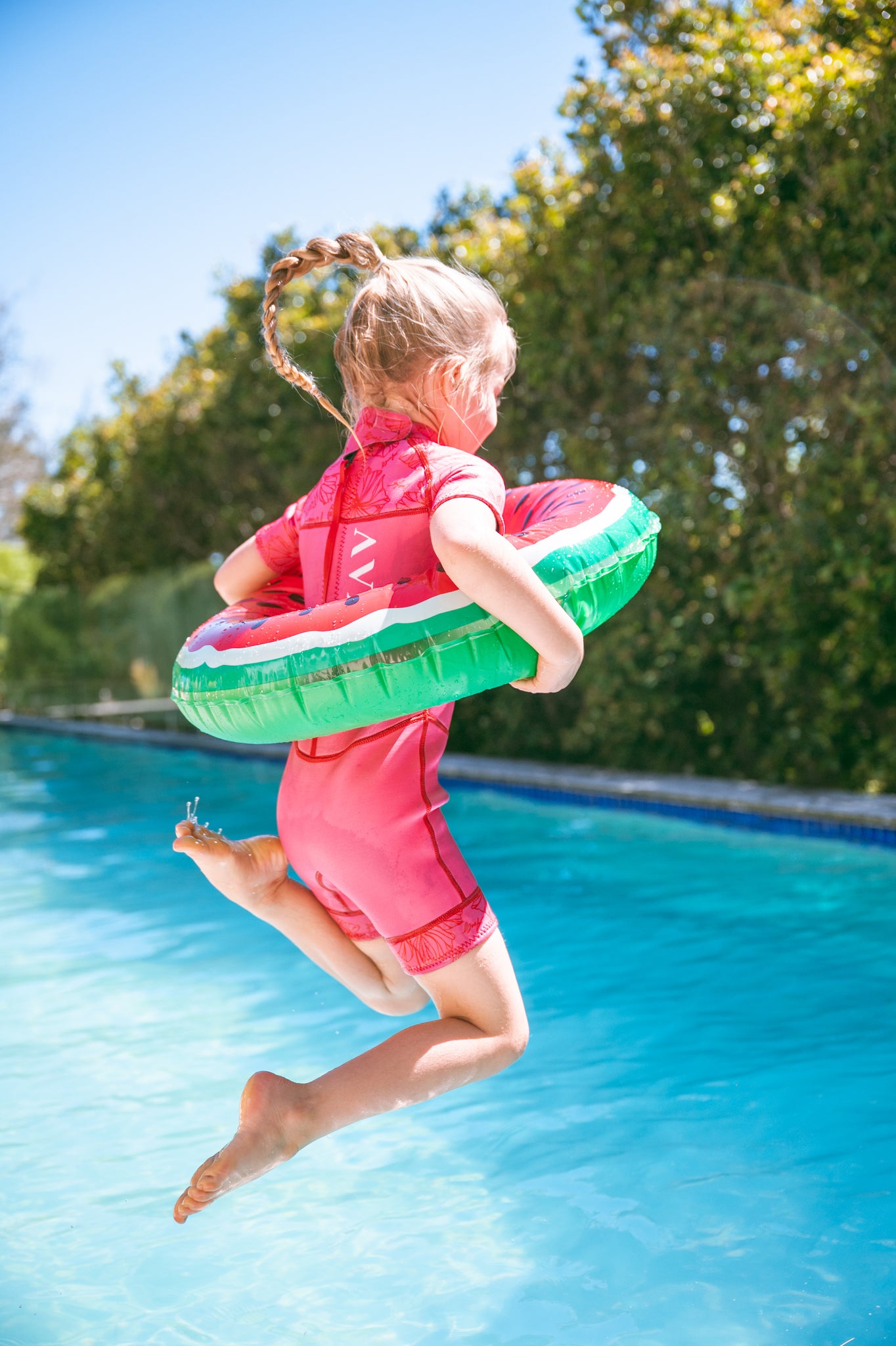 Girl in AVALY springsuit jumping into the pool on a warm day
