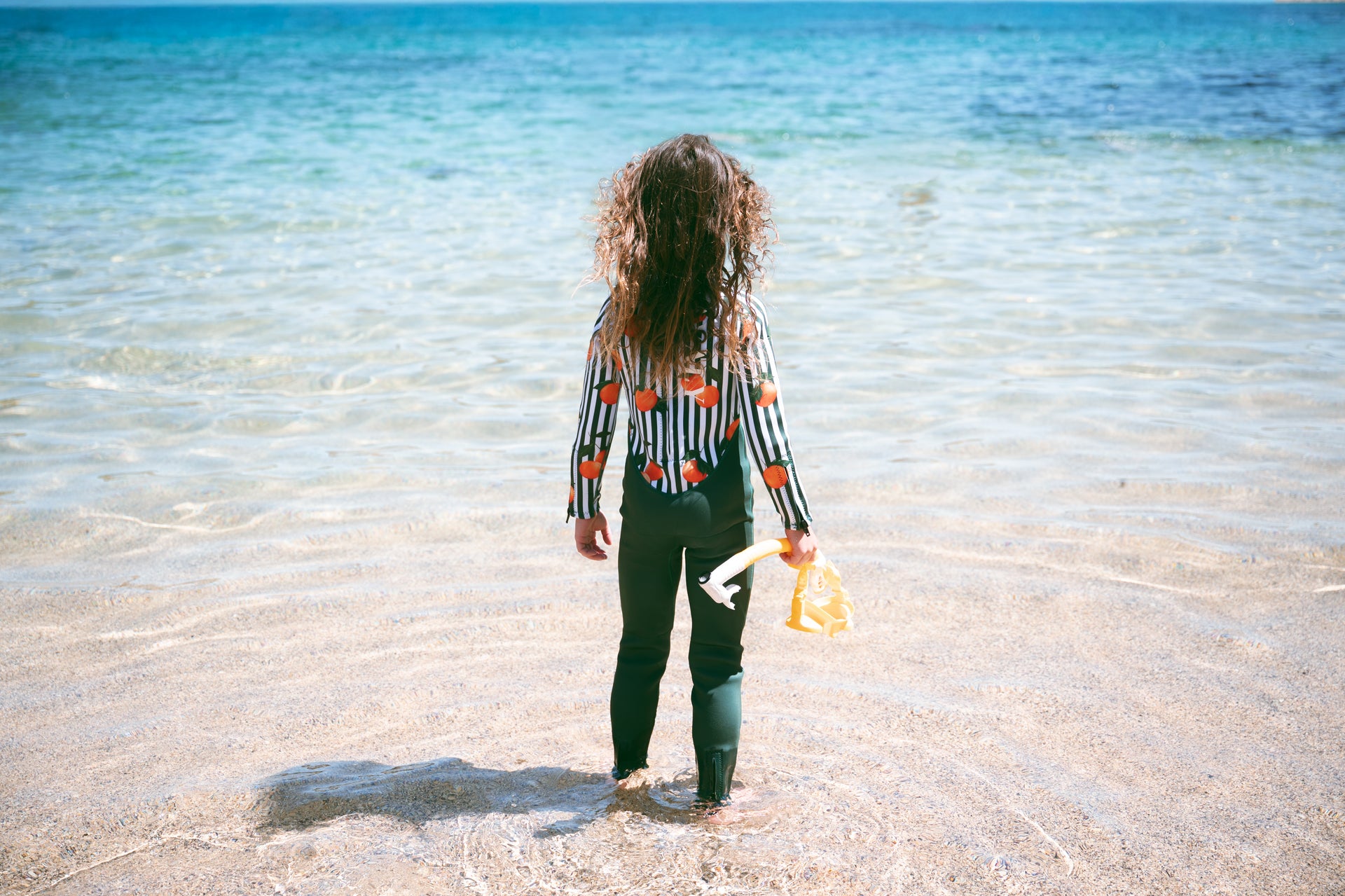 Child standing in crystal clear ocean water