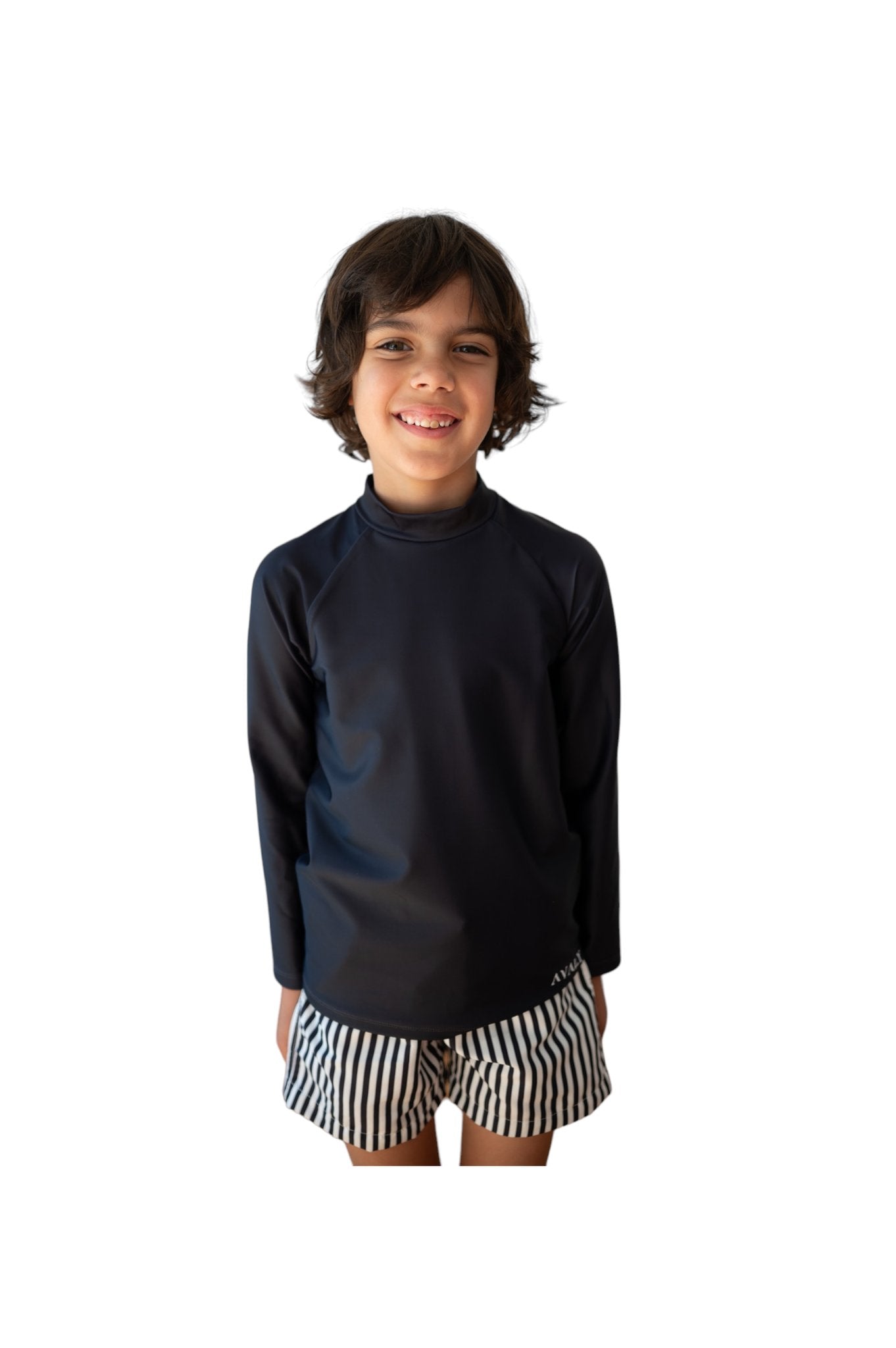 Child model wearing Navy Rash Top Byron with black and white striped swim shorts, smiling against white background