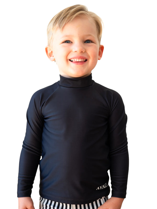 Smiling blonde child wearing navy Byron sustainable rash top with high neck and long sleeves