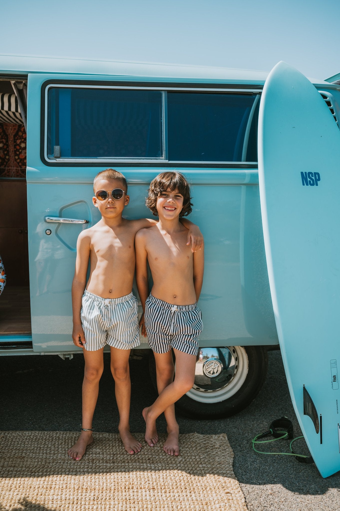 Two boys in striped board shorts standing by turquoise van, one wearing Sage striped Kids Board Shorts Vincentia