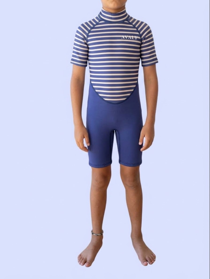 Child wearing the Blue Stripe Kids Wetsuit, a short sleeve springsuit with a navy and cream striped top and solid navy shorts