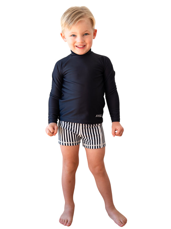 Young boy wearing navy long-sleeve rashie with Navy Striped Bondi Sustainable Kids Trunks featuring black and white stripes