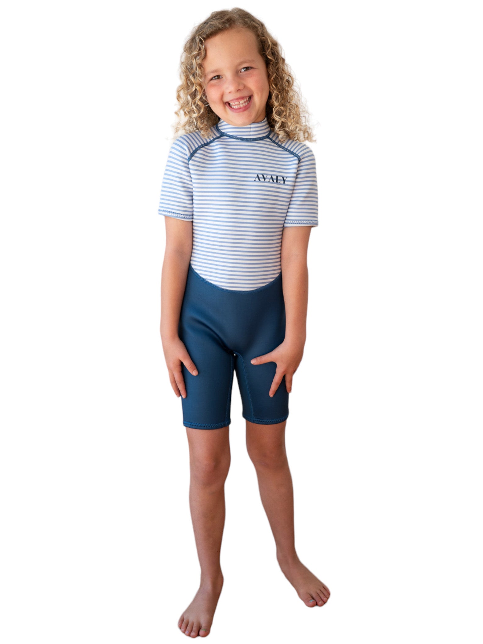 Girl wearing Navy Stripe Kids Wetsuit with blue and white striped top and navy shorts, smiling on white background