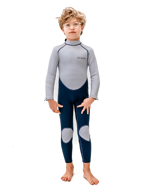 Child wearing Navy Striped Avalon sustainable wetsuit with blue and white striped rash guard and navy neoprene pants