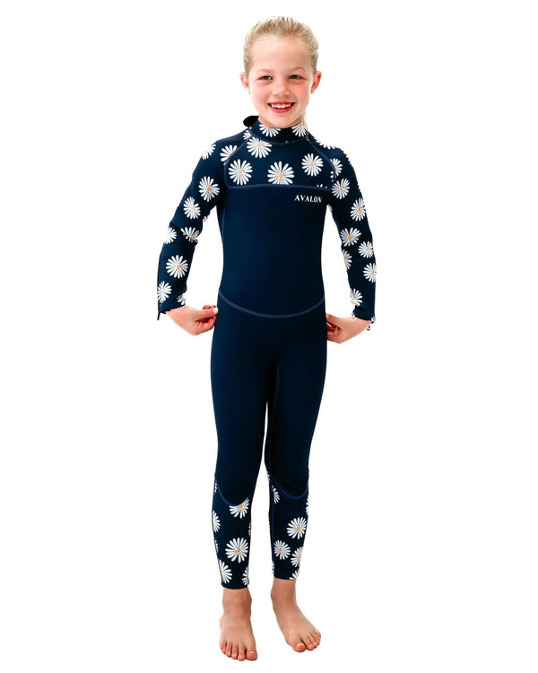 Child model wearing Navy Daisy Mollymook wetsuit with white daisy pattern on sleeves and lower legs